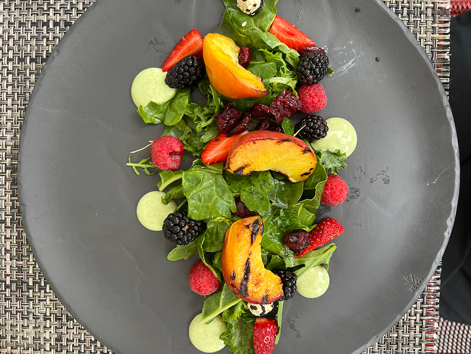 A gourmet salad with grilled peaches, fresh berries, arugula, and green dressing, prepared by one of the private chefs at the Fluenz Spanish Immersion in Mexico City, where every meal is customized to address guests’ dietary preferences and restrictions.
