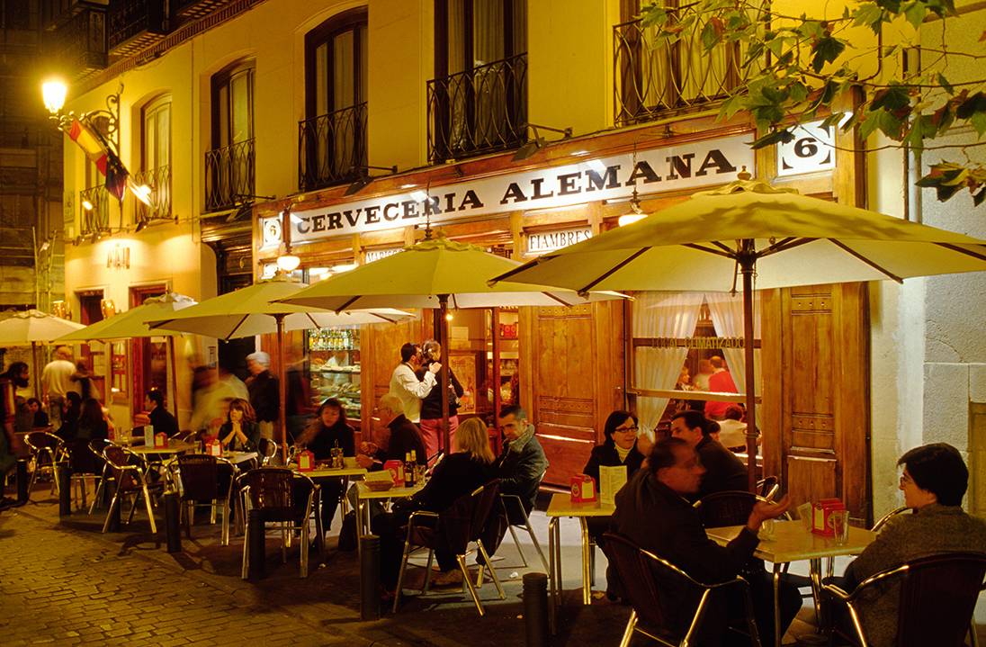 Evening scene of a traditional café terrace in Madrid, where learners from the Fluenz Luxury Spanish Immersion enjoy real-life language practice. The program blends personalized Spanish instruction with exclusive cultural experiences across Spain’s most iconic settings.