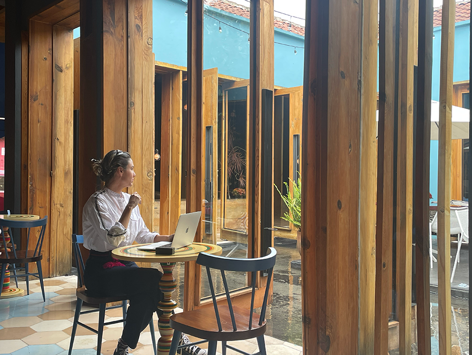 Sonia Gil, founder of Fluenz, working on her laptop in a beautifully designed space. She leads the team behind the Fluenz Online Spanish Immersion, a program that helps adults learn Spanish online through personalized, one-on-one sessions conducted via Zoom with expert Spanish tutors.