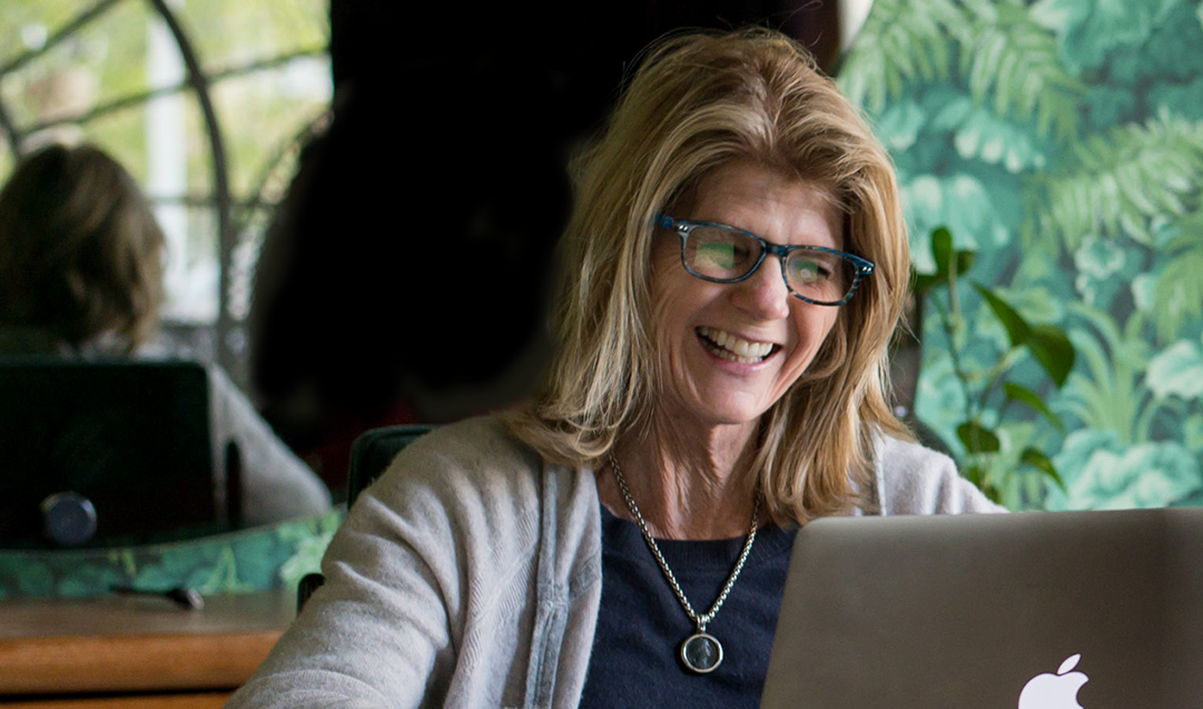 An adult learner smiles during a live one-on-one session with her Spanish coach on her laptop, part of the Fluenz Online Spanish Immersion. This exclusive program allows professionals to learn Spanish online through personalized coaching via Zoom, offering the best online Spanish immersion program for adults seeking fluency with expert tutors.