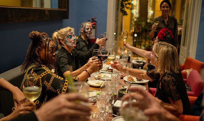 Students from the Fluenz Spanish Immersion in Mexico City raise their glasses during a festive dinner celebrating Día de los Muertos. The scene reflects the warmth, cultural connection, and immersive experiences that define the best program to learn Spanish in Mexico.
