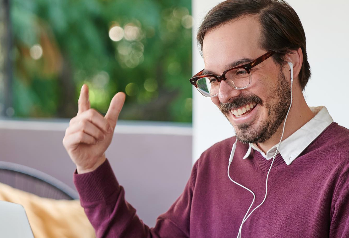 A Spanish tutor leading a live online Spanish immersion session, smiling and gesturing as he works one-on-one with a learner. The scene reflects the structured, intensive approach of the best learn-Spanish-online and learn-Spanish-on-Zoom programs in the world.