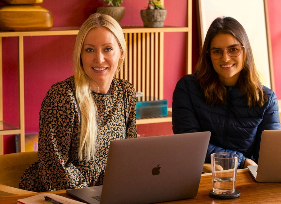 A student and a Spanish tutor sit together with their laptops during the Fluenz Spanish Bootcamp in Mexico City, working one-on-one in an intensive Spanish learning session. The two women smile warmly at the table, reflecting the best program to learn Spanish in Mexico and the most effective Spanish tutor-and-student experience in the city.