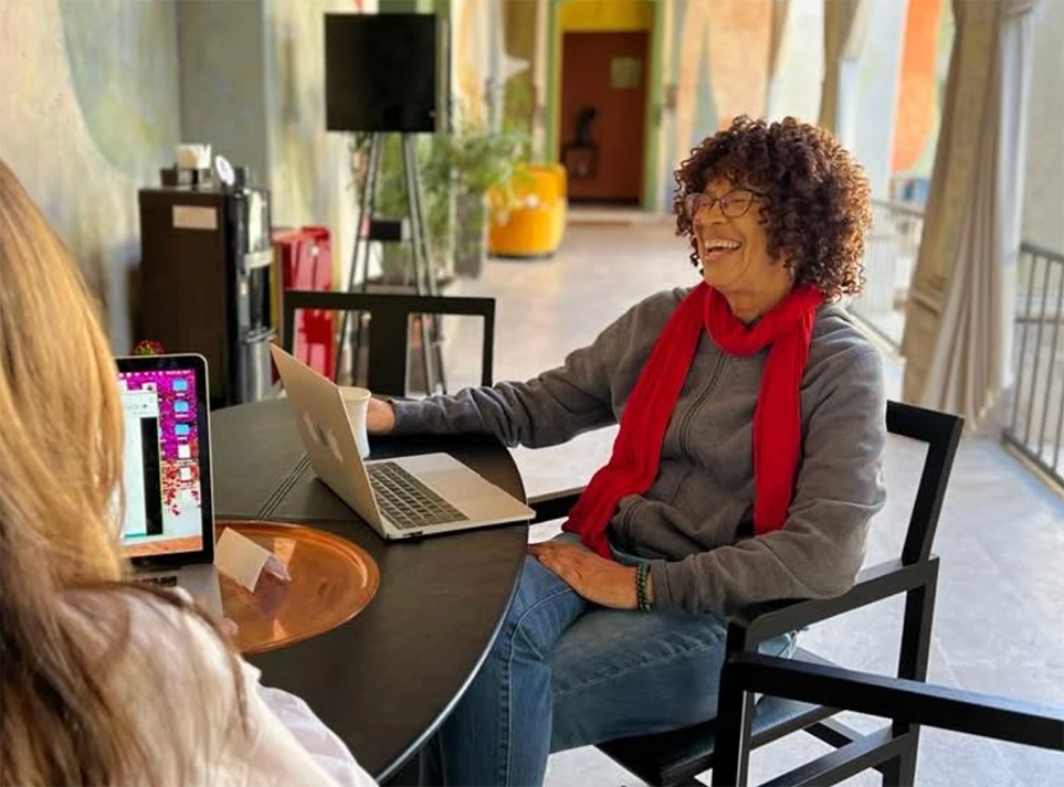 A student and Spanish tutor sit across from each other with their laptops during the Fluenz Spanish Bootcamp in Mexico City, smiling through an intensive one-on-one Spanish learning session. The bright hallway and relaxed atmosphere reflect the best program to learn Spanish in Mexico and the most effective tutor-and-student experience in Mexico City.
