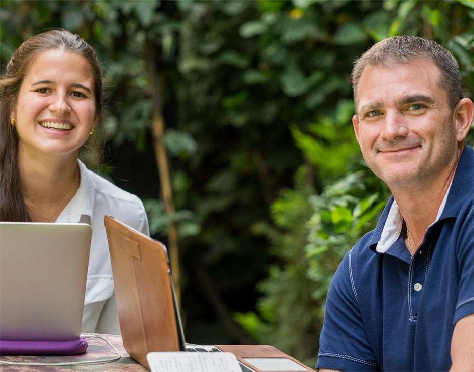 A student and Spanish tutor sit outdoors with their laptops during the Fluenz Spanish Bootcamp in Mexico City, smiling as they work through intensive one-on-one Spanish learning. Surrounded by greenery, the scene reflects the best program to learn Spanish in Mexico and the most effective Spanish tutor-and-student experience in Mexico City.