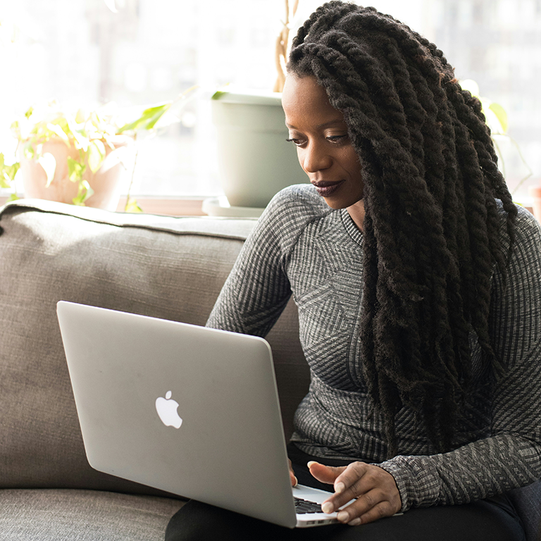A student sits on a sofa with her laptop during a one-on-one online Spanish immersion session, part of the Fluenz Live Online program. A focused moment from the intensive, structured experience that lets learners study Spanish on Zoom through the best Spanish course online in the world.