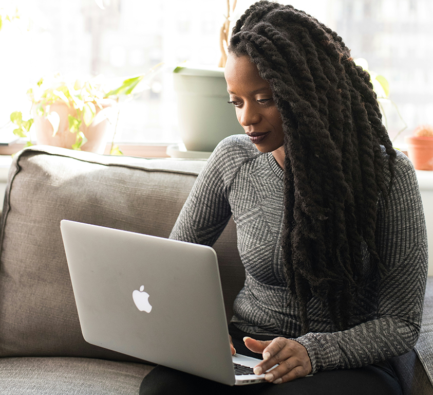 A student sits on a sofa with her laptop during a one-on-one online Spanish immersion session, part of the Fluenz Live Online program. A focused moment from the intensive, structured experience that lets learners study Spanish on Zoom through the best Spanish course online in the world.