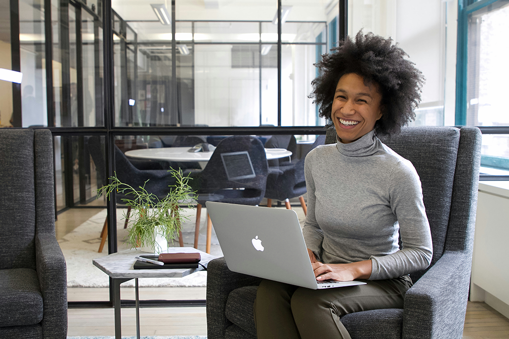A student smiling while working on a laptop during an online Spanish immersion session, representing live online Spanish learning on Zoom with one-on-one intensive, structured instruction through the best online Spanish course in the world.