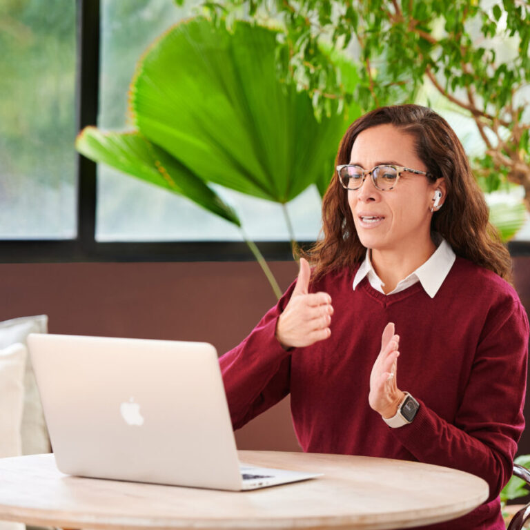 Fluenz Spanish tutor in a burgundy sweater teaching Spanish online, leading a live one-on-one immersion session with clear structure and real-time conversation.