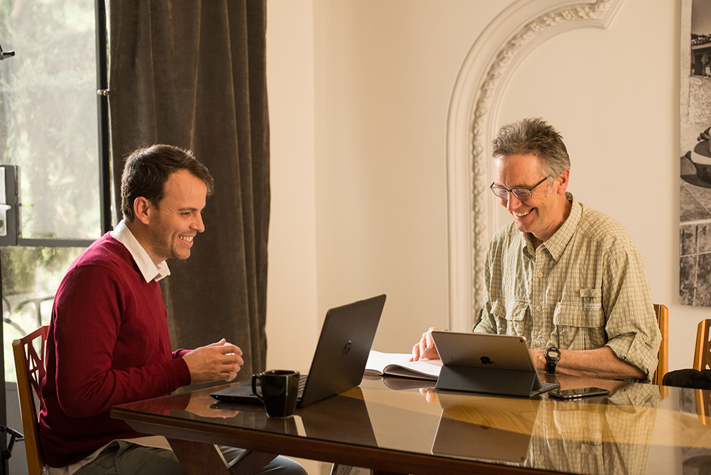 Fluenz Spanish Bootcamp one-on-one session with an adult learner and a Fluenz Spanish tutor working together at a table with laptops and notebooks in an immersive learning environment.