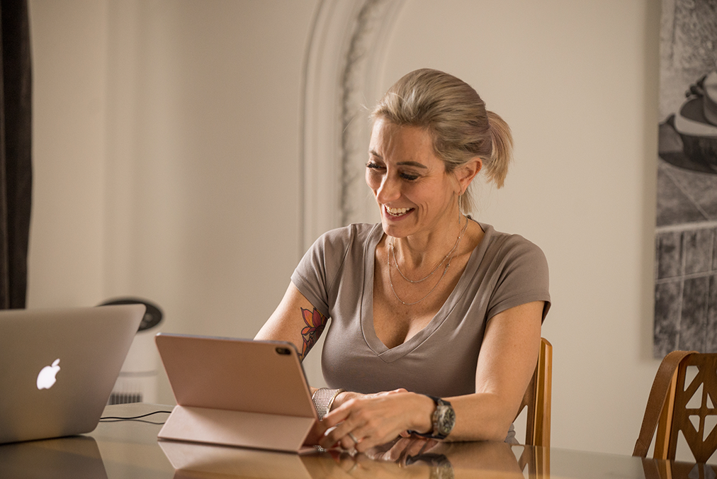 Adult learner participating in Fluenz Live Online Spanish immersion, smiling while working one-on-one with a tablet during a personalized online Spanish lesson.