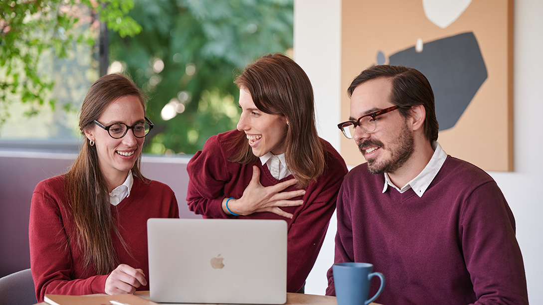 The world’s best team of Spanish tutors collaborating at Fluenz’s highest-rated, most intensive and most effective online Spanish immersion program, gathered around a laptop and smiling as they review a lesson together.