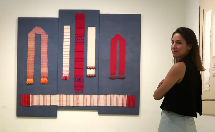 Sonia Gil, Fluenz founder, stands in an art gallery in Oaxaca during the Fluenz Spanish Immersion, beside vibrant textile artwork that reflects the cultural depth of one of the most exclusive and effective Spanish programs in the world.