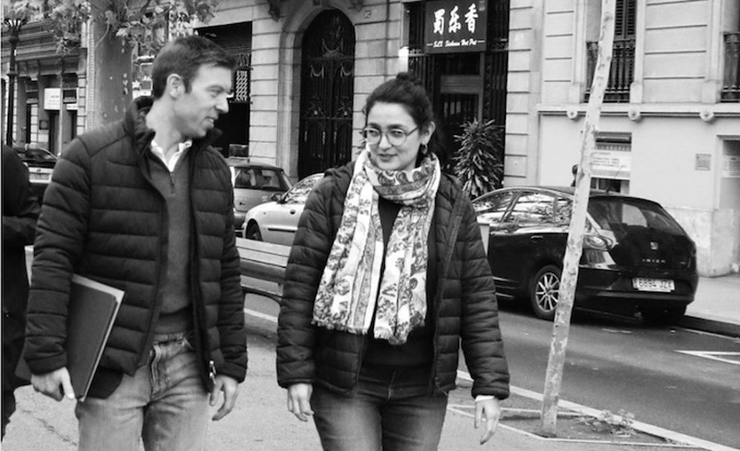 A Fluenz coach and learner walk through a Madrid street in conversation, continuing their immersive Spanish learning experience beyond the classroom in a real-world setting.