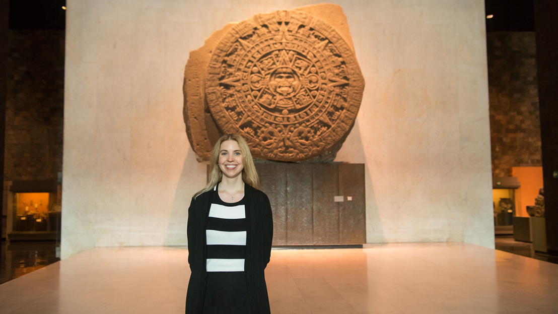 A Fluenz participant stands inside the National Museum of Anthropology in Mexico City in front of the Aztec Sun Stone, experiencing one of the world’s most important cultural landmarks as part of the Fluenz Spanish Immersion.