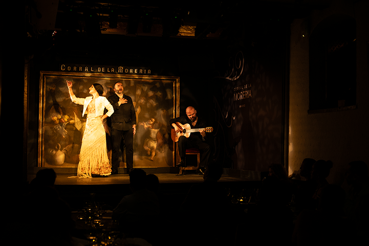 A flamenco dancer performs on stage alongside a singer and guitarist at Corral de la Morería in Madrid, offering an intimate cultural experience during the Fluenz Spanish Immersion.