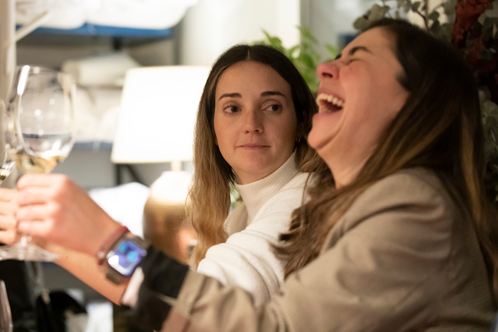 Adult learners sharing a lighthearted moment over wine during an evening gathering in the Fluenz Spanish Immersion in Madrid.