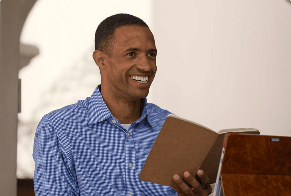Fluenz Spanish Bootcamp participant smiles while holding an open notebook during a Spanish lesson.