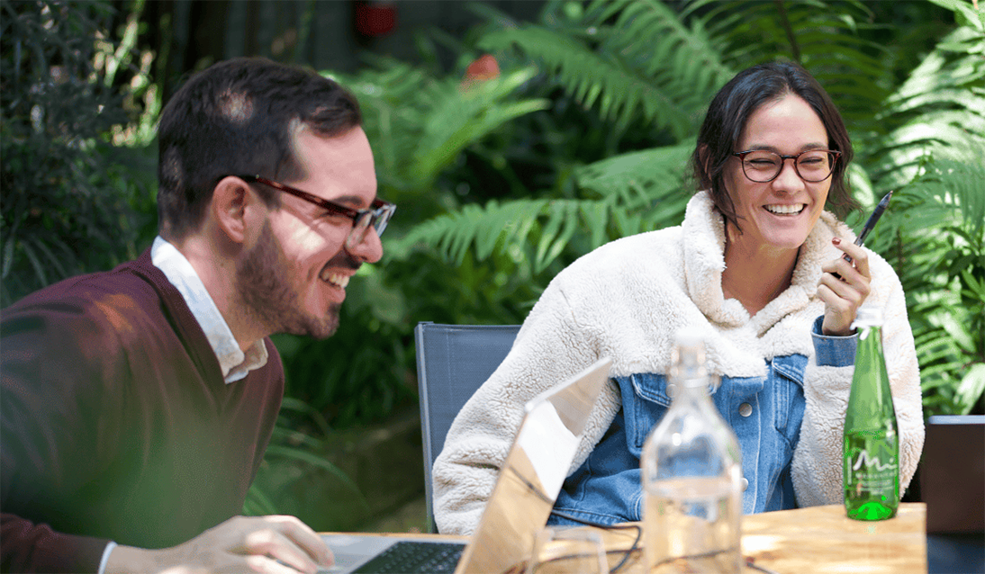 Fluenz Spanish Bootcamp participant laughs with a tutor during a one-on-one outdoor lesson.