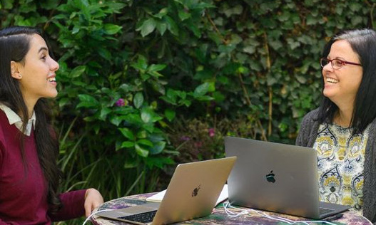 Fluenz Spanish Bootcamp participant practices one-on-one with a tutor during an outdoor laptop lesson.