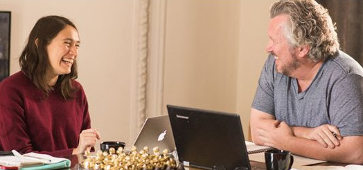 Fluenz Spanish Bootcamp participant laughs with a tutor during a personalized lesson using laptops.