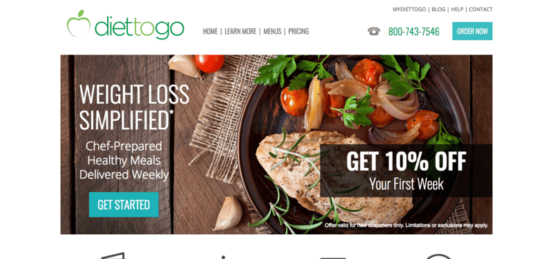 Diet to Go website screenshot showing chicken with a salad on a wooden table with garlic and tomatoes