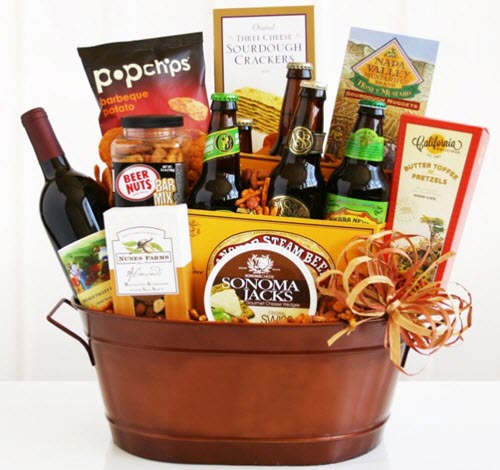 A copper tub containing a large selection of snacks, beer and a bottle of wine.