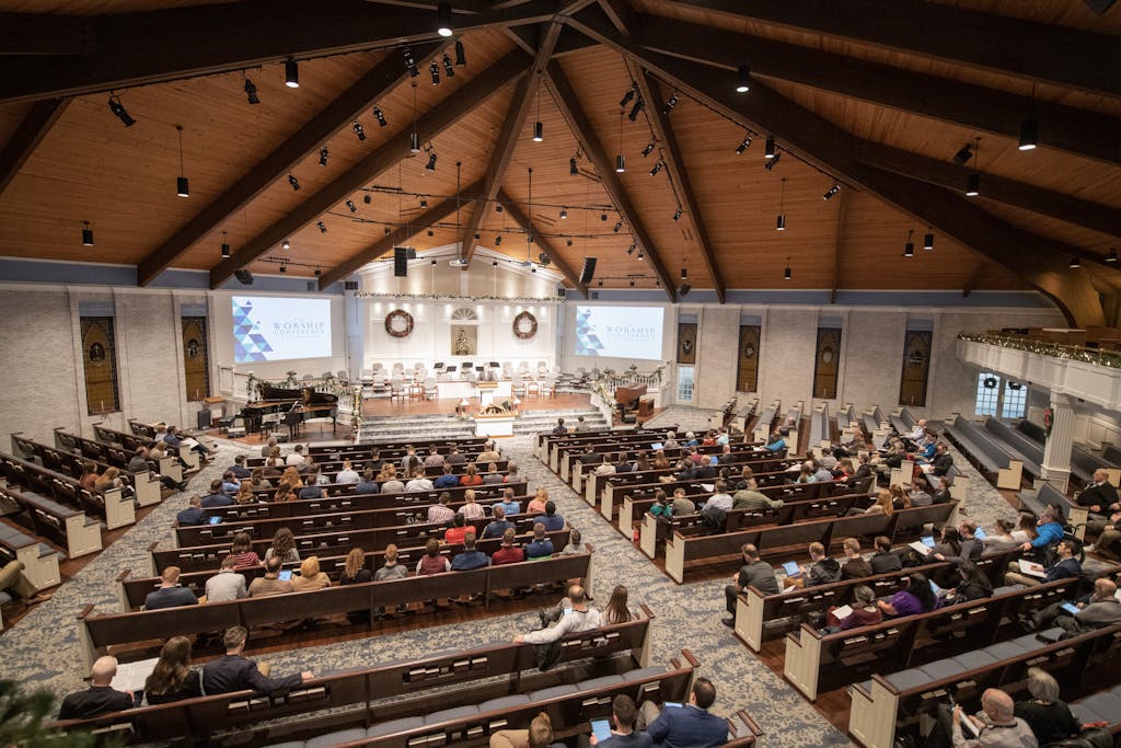 Large congregation gathered in church with wooden interiors, engaged in a service.