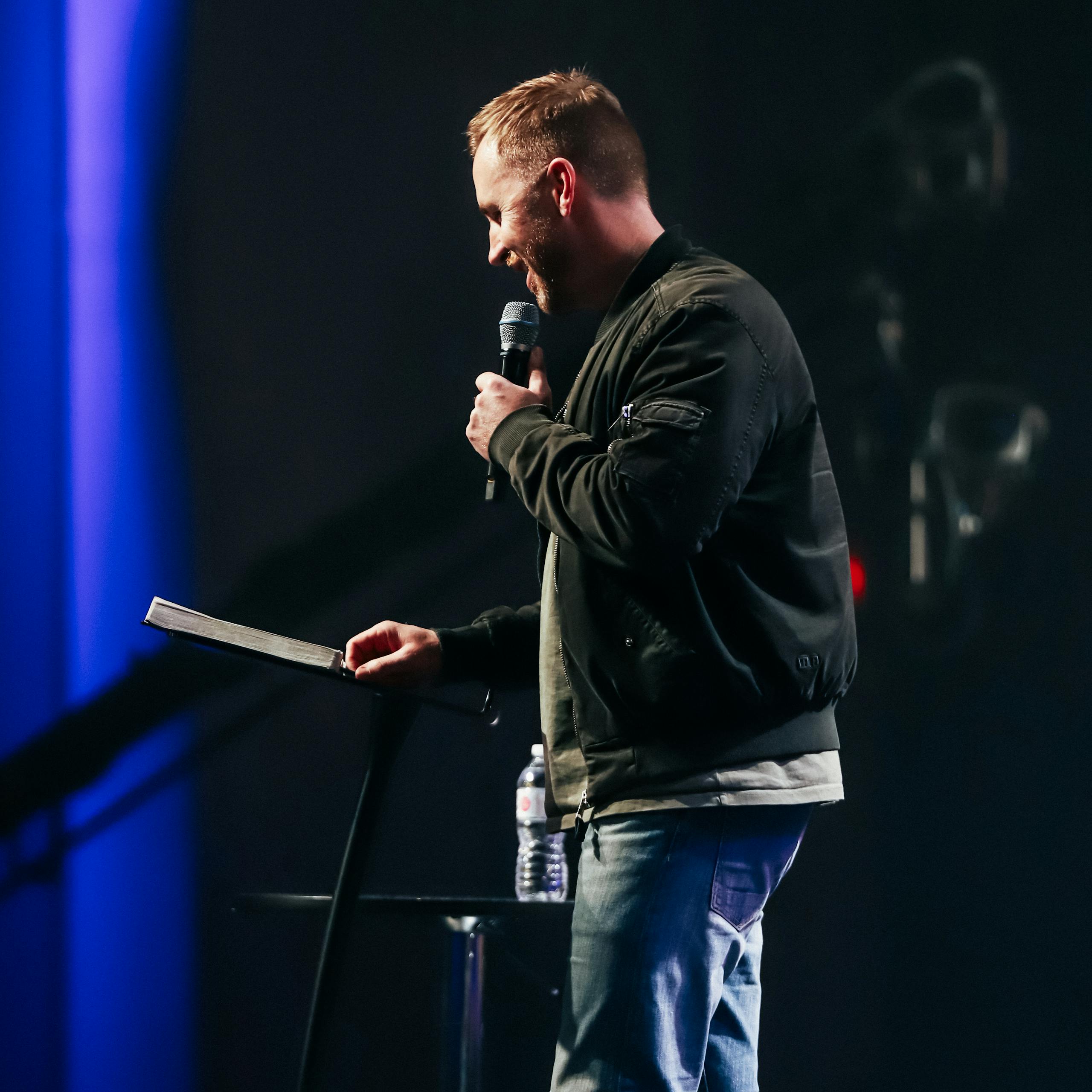Dynamic speaker passionately delivering a talk to an audience, microphone in hand.