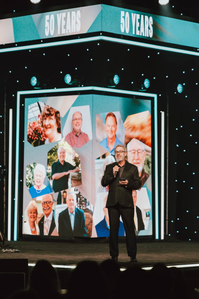 Steve Mickel celebrates the 50 and 60 year service awards on stage at Foursquare Connection 2026
