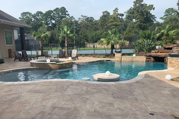 Custom landscaping surrounding a residential pool during the final build stages