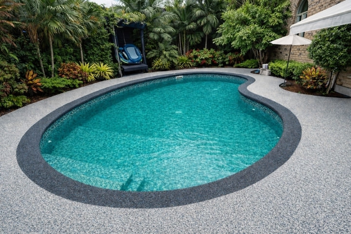 Teal tiled pool surrounded by a slip resistant rubber pool deck
