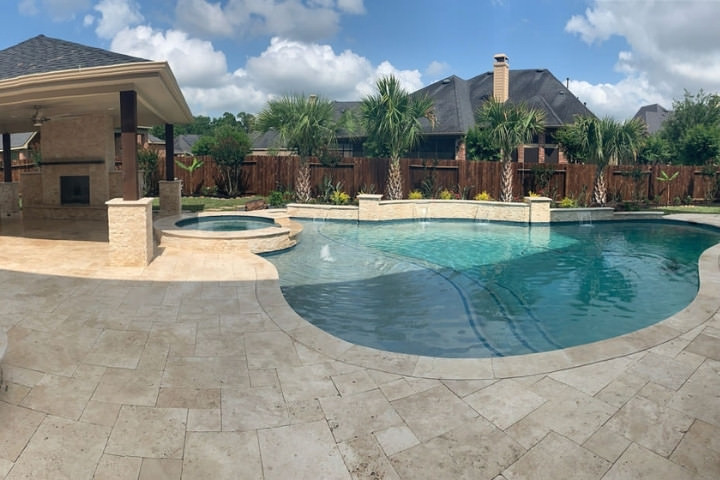 Elegant pool and spa surrounded by travertine pavers in a stylish backyard setting