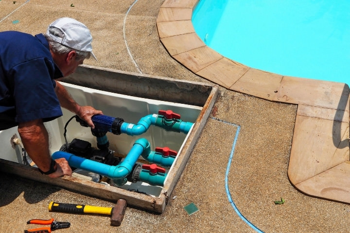 Houston pool technician inspecting pool plumbing and equipment during maintenance evaluation