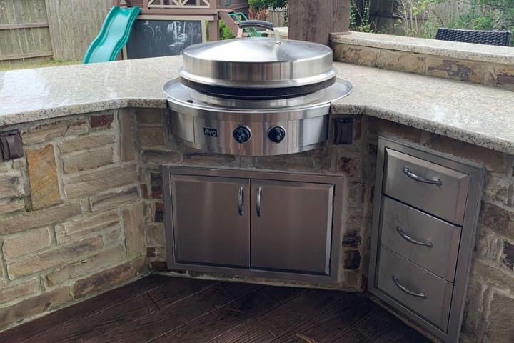 Houston outdoor kitchen with stainless steel cabinet storage, corner cooktop, stone cladding, and granite countertop