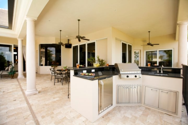 Spacious outdoor kitchen featuring soft neutral finishes, dark countertops, and built in grill and storage