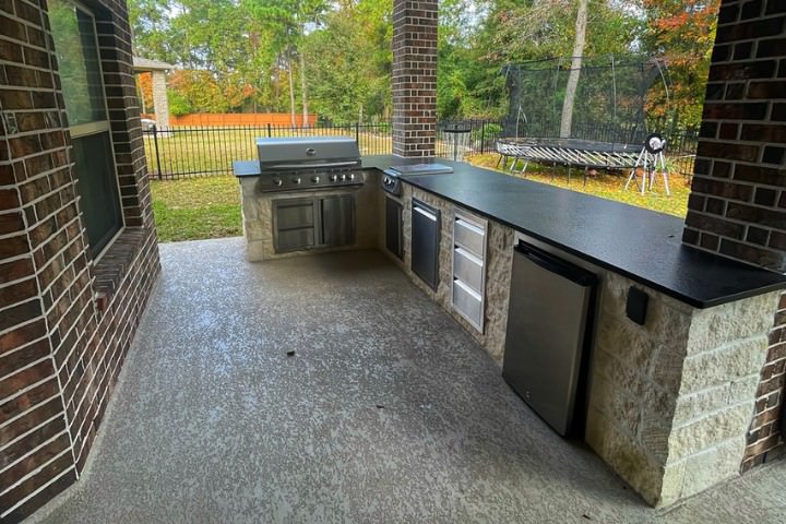 Houston outdoor kitchen with durable long black countertop, built-in stainless grill, and stone support base