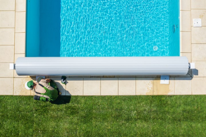 Energy-efficient automatic pool cover installed across a residential swimming pool to reduce evaporation