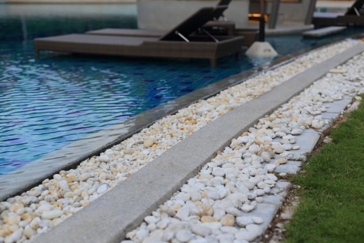 Poolside drainage border with smooth stones for a sustainable pool design