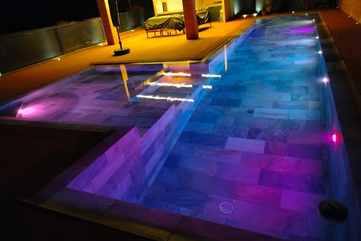 Modern pool illuminated with automated LED lighting for an energy-efficient nighttime backyard experience