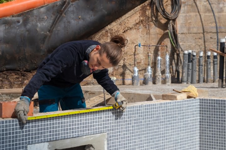 Pool construction worker measuring the edge of a pool under construction
