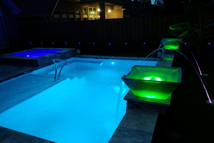 Lit spill bowls add colorful lighting accents to a modern pool design