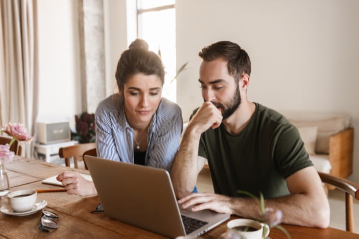 Homeowners comparing pool automation options and installation costs on a laptop