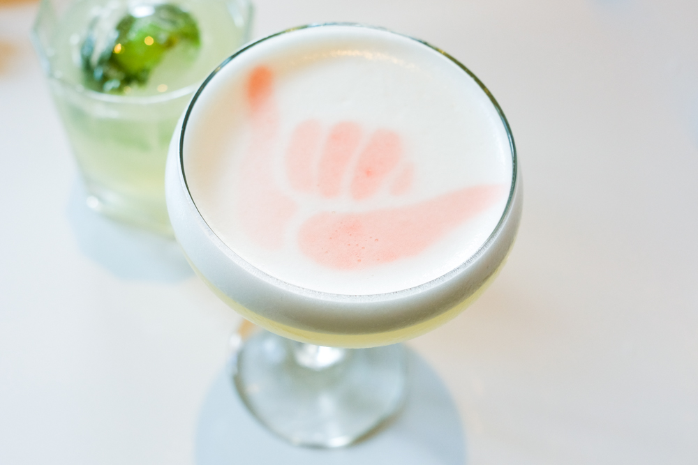Live a little aloha with the Shaka Sour, one of Stripsteak's signature cocktails made with Death's Door gin, lillet blanc, yuzu, mangosteen and foamy egg whites, which make the perfect canvas for a spayed shaka. It's herby, tarty and creamy all at the same time.
