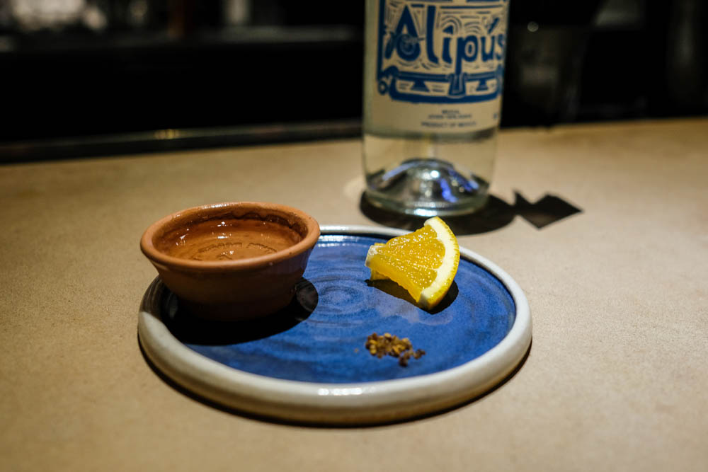 Here's how to enjoy mezcal. Sip some from the copito first. Next dip the orange segment in worm salt and bite. Follow your bite with another sip.