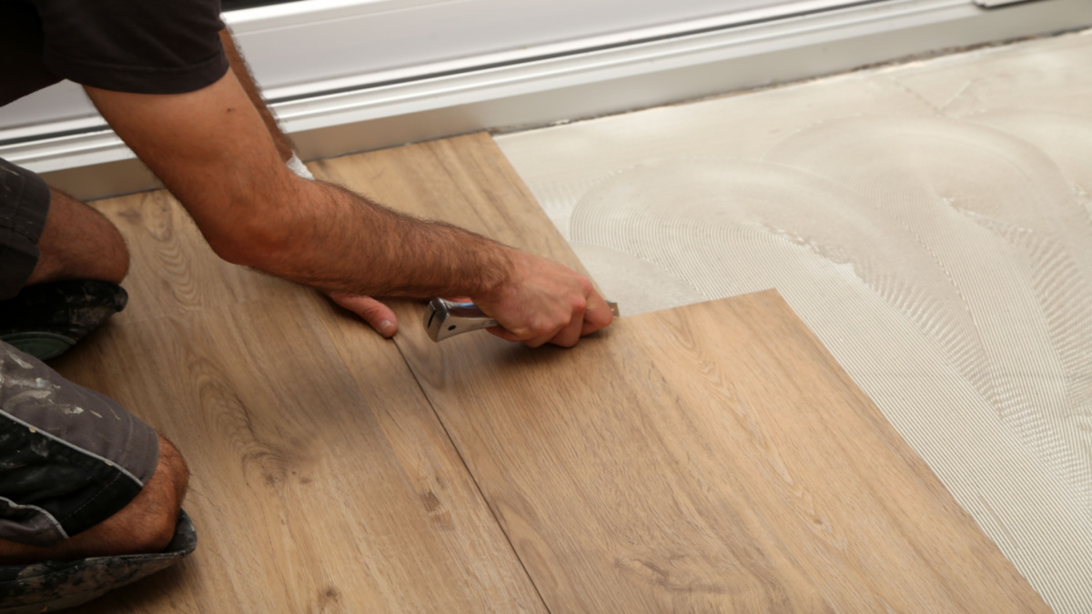 Installer laying LVT flooring planks on prepared floor