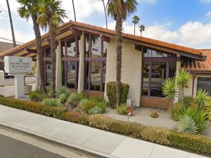 Street view of Pacific Palms with monument sign and palm trees