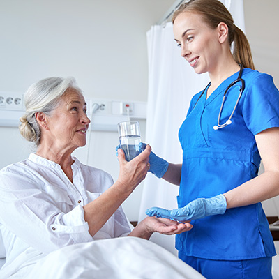 Female nurse handing elderly resident a glass of water