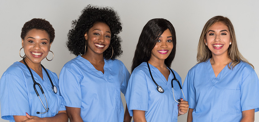 Four smiling women in blue scrubs