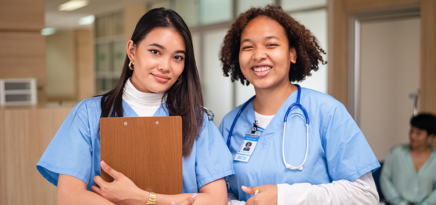 Two smiling medical professionals in blue scrubs